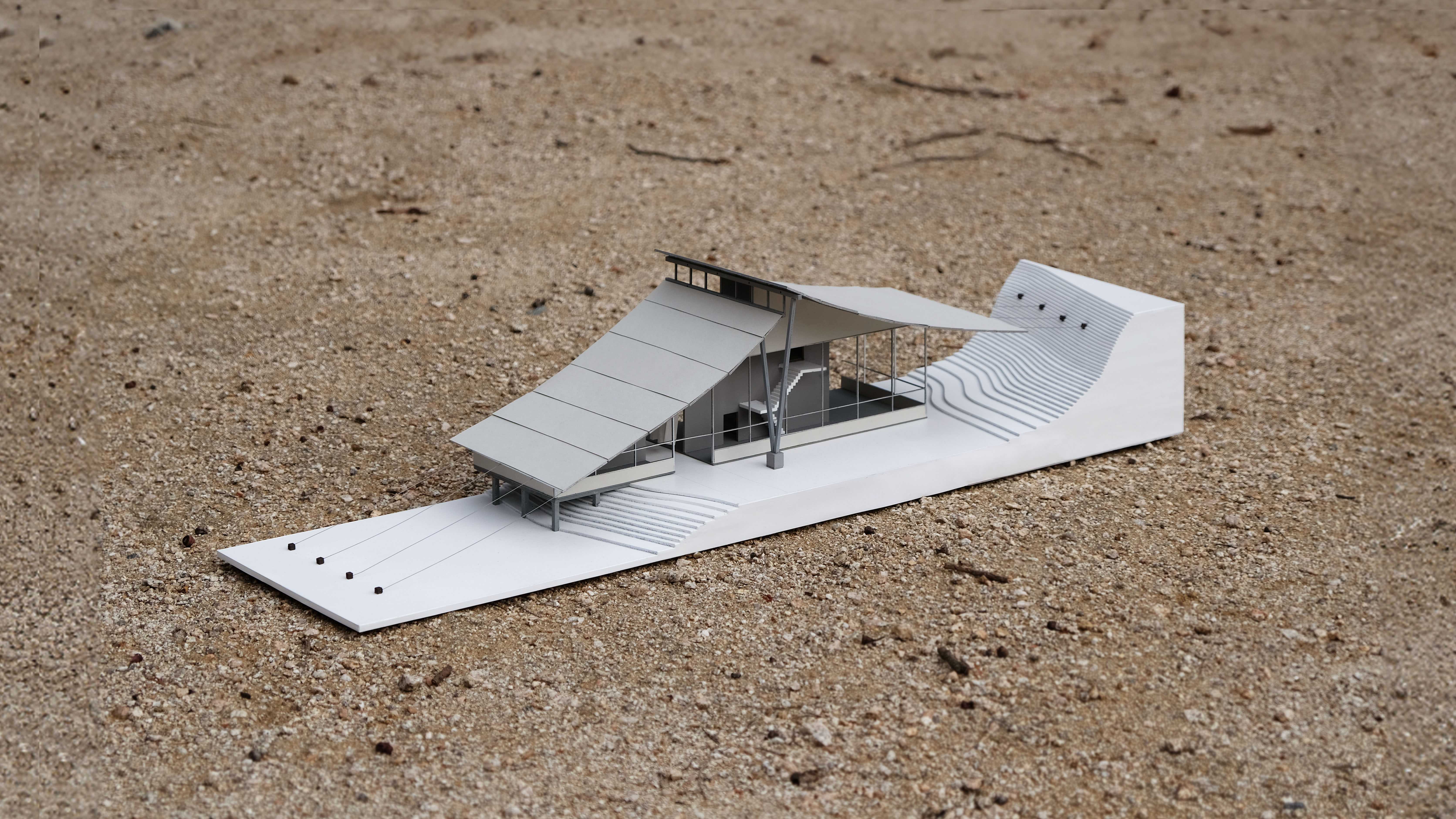 The walls and roof are clad in corrugated steel sheeting, complementing the steel-framed curtain wall and reinforcing the idea of a lightweight envelope surrounding a solid concrete core.
